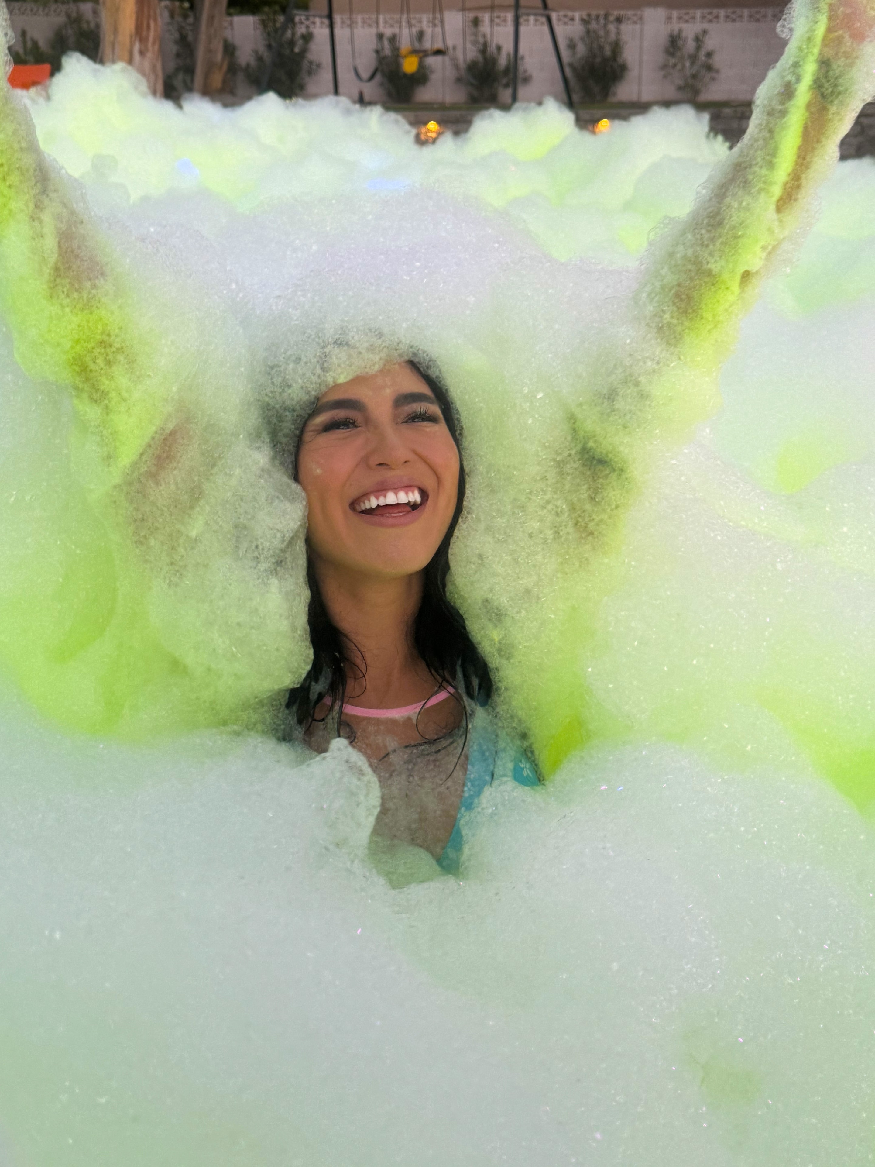 Woman laughing surrounded by neon green foam